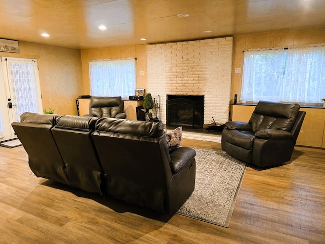 living room featuring recessed lighting, a brick fireplace, and wood finished floors