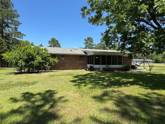 142 Elva Cir, Enigma, GA 31749 - rear view of house featuring a sunroom, a lawn, and brick siding