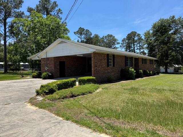 142 Elva Cir, Enigma, GA 31749 - view of front facade featuring driveway, a front yard, brick siding, and an attached carport