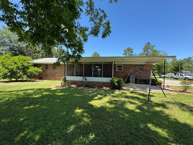 142 Elva Cir, Enigma, GA 31749 - rear view of house featuring a yard, brick siding, and a sunroom