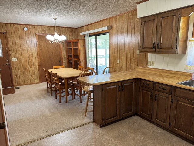 142 Elva Cir, Enigma, GA 31749 - kitchen with wood walls, a textured ceiling, a chandelier, light countertops, and a peninsula