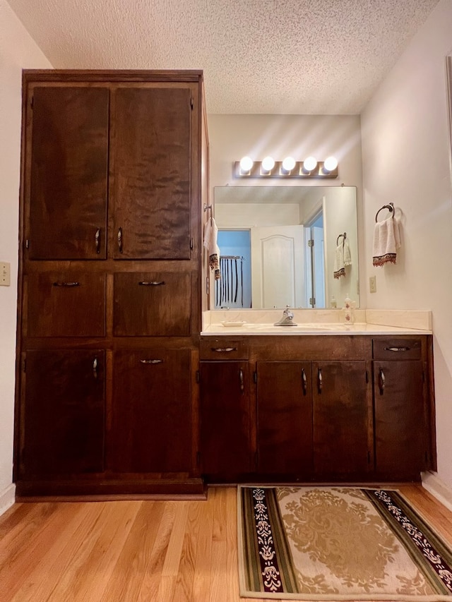 109 Preston Dr, Fitzgerald, GA 31750 - bathroom with wood finished floors, double vanity, and a textured ceiling