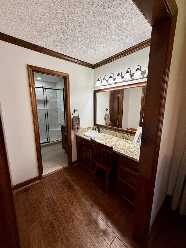 7222 E Northgate Dr, Tifton, GA 31794 - bathroom featuring wood finished floors, a textured ceiling, ornamental molding, vanity, and an enclosed shower
