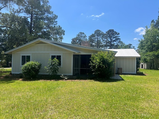 315 Newton Dr, Adel, GA 31620 - view of front of house featuring a front yard, a chimney, board and batten siding, and a sunroom