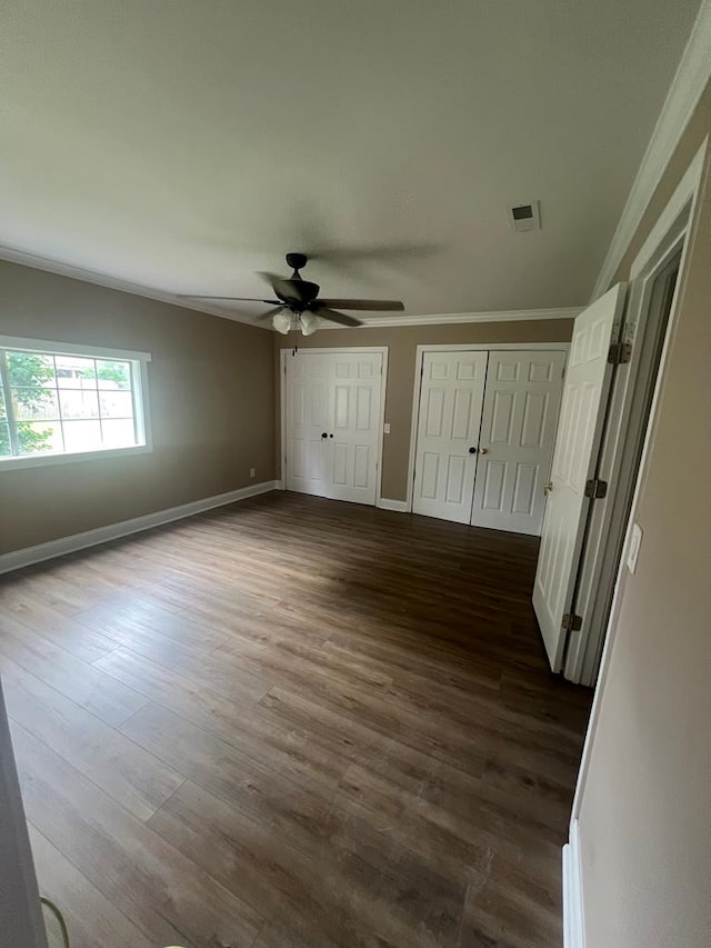 315 Newton Dr, Adel, GA 31620 - unfurnished bedroom featuring crown molding, multiple closets, dark wood-type flooring, baseboards, and a ceiling fan