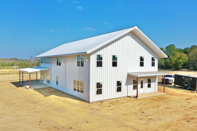 rear view of property featuring board and batten siding and metal roof