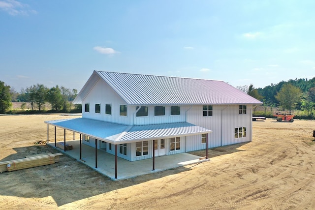 back of property featuring a patio, french doors, metal roof, and dirt driveway