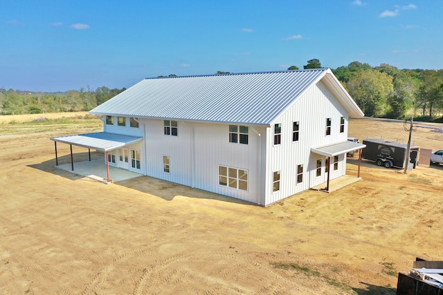 back of property with a carport, metal roof, driveway, and a patio area