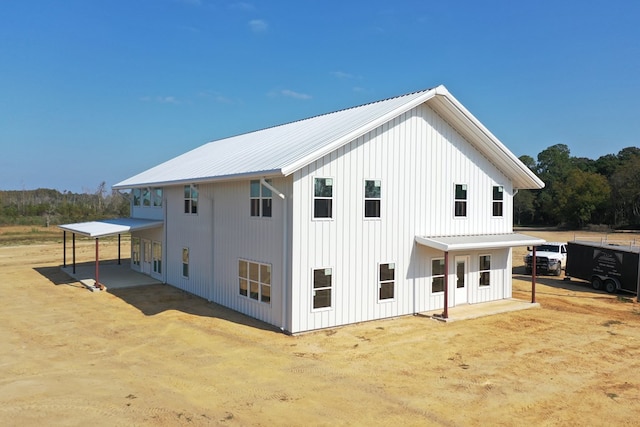 exterior space with a carport, metal roof, board and batten siding, and a patio