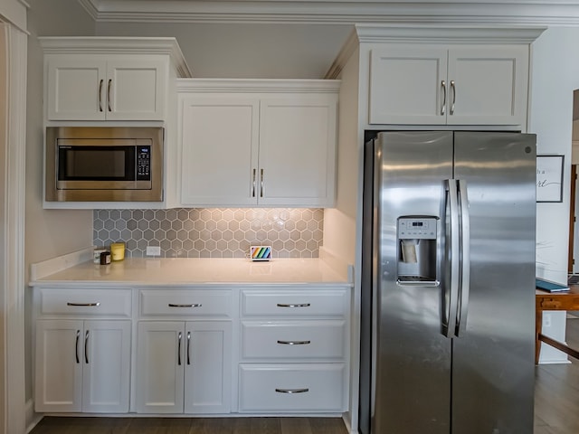kitchen with tasteful backsplash, white cabinetry, stainless steel appliances, and light countertops