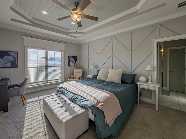bedroom featuring carpet floors, a decorative wall, visible vents, crown molding, and a tray ceiling