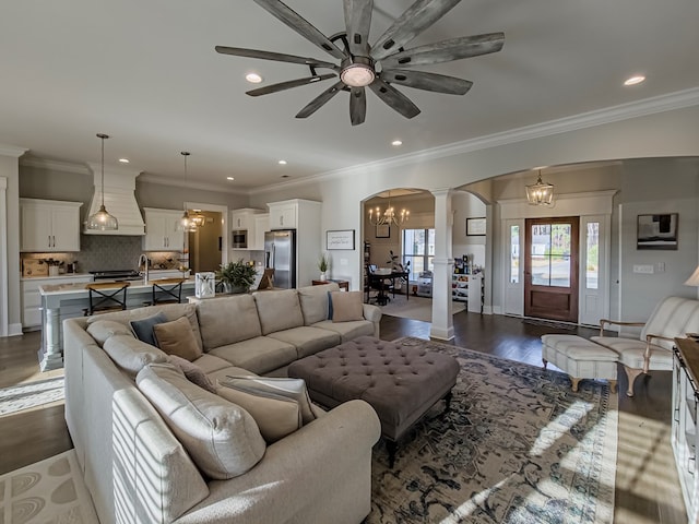 living room featuring recessed lighting, ornate columns, ornamental molding, arched walkways, and ceiling fan with notable chandelier