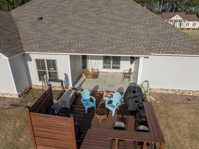 back of property featuring a deck, a patio area, and roof with shingles