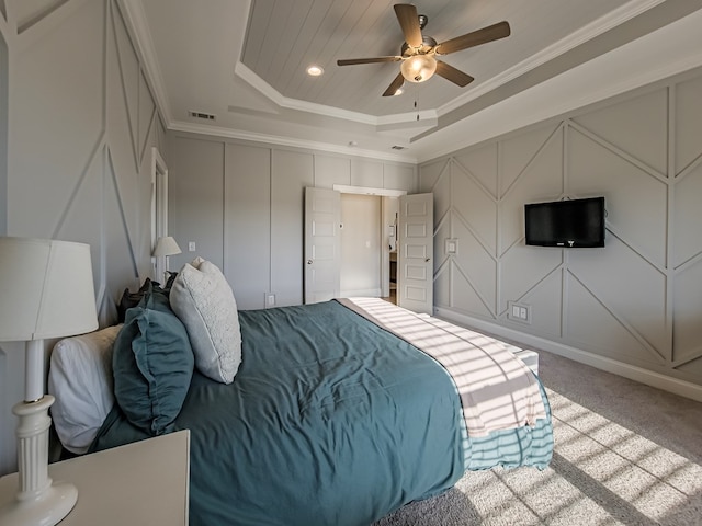 carpeted bedroom featuring visible vents, a tray ceiling, crown molding, and a decorative wall