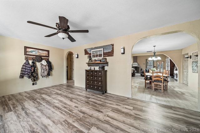 living room featuring ceiling fan with notable chandelier and wood-type flooring