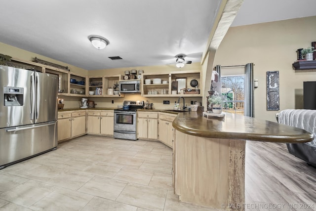 kitchen with light tile patterned flooring, kitchen peninsula, ceiling fan, appliances with stainless steel finishes, and sink