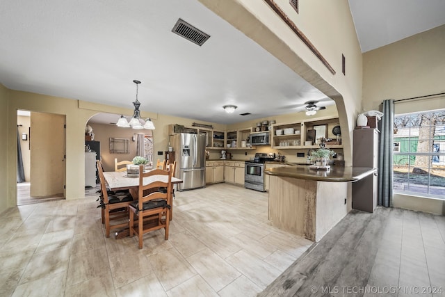 kitchen with ceiling fan, kitchen peninsula, pendant lighting, appliances with stainless steel finishes, and light tile patterned floors