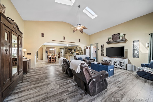 living room featuring a skylight, hardwood / wood-style floors, high vaulted ceiling, and ceiling fan