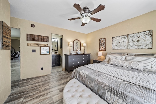 bedroom featuring sink, ensuite bath, wood-type flooring, and ceiling fan