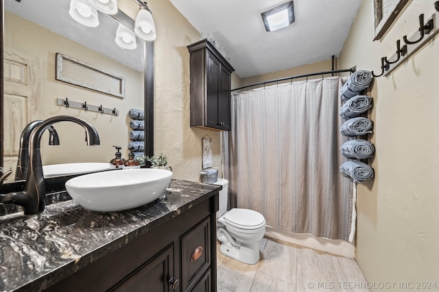 bathroom with tile patterned flooring, toilet, vanity, and a textured ceiling