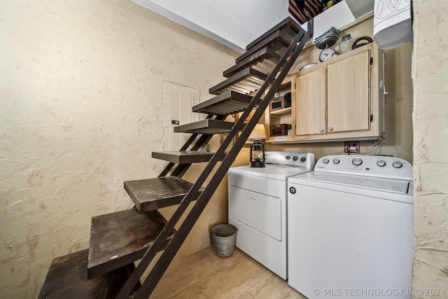 laundry room with cabinets, light tile patterned floors, and washing machine and clothes dryer