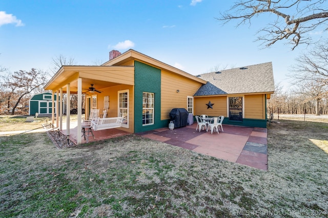 back of house featuring a shed, ceiling fan, a lawn, and a patio area