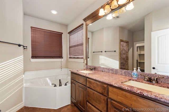 bathroom with a wealth of natural light, vanity, and a bathing tub