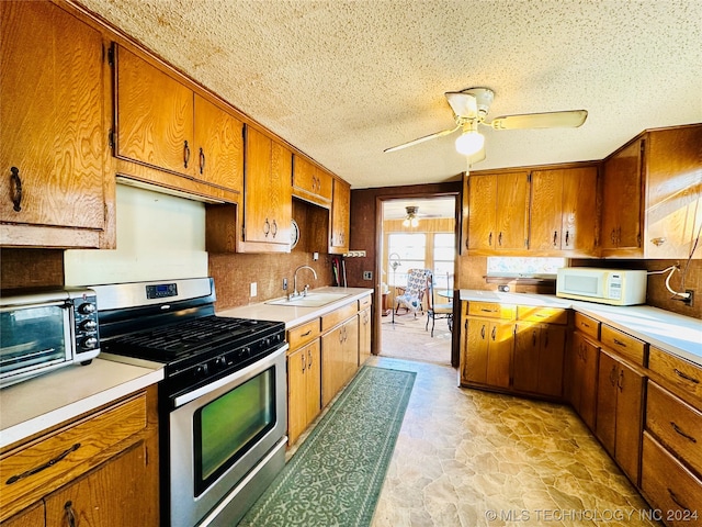 kitchen featuring ceiling fan, light tile floors, a textured ceiling, sink, and gas stove