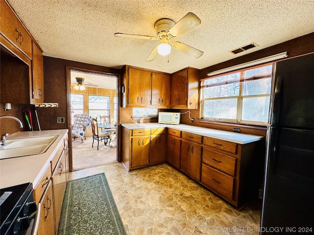 kitchen featuring light tile flooring, ceiling fan, a textured ceiling, sink, and black fridge