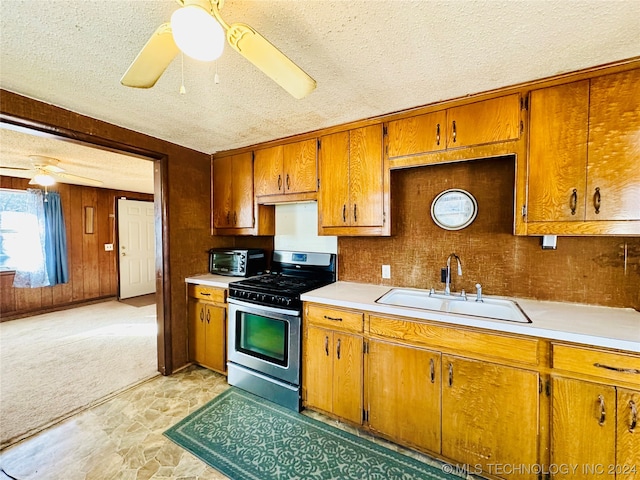 kitchen featuring light colored carpet, ceiling fan, a textured ceiling, sink, and stainless steel gas range oven