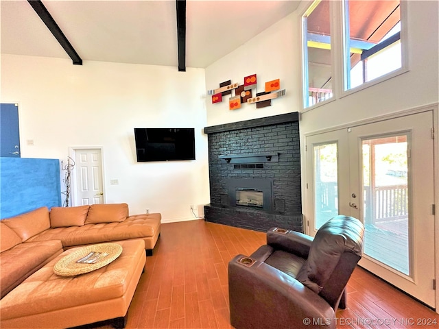 living room featuring beamed ceiling, hardwood / wood-style floors, high vaulted ceiling, and a fireplace