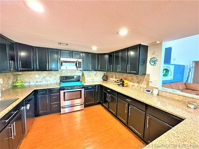 kitchen featuring a textured ceiling, light hardwood / wood-style flooring, light stone counters, and appliances with stainless steel finishes