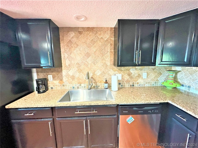 kitchen featuring a textured ceiling, light stone counters, sink, decorative backsplash, and stainless steel dishwasher