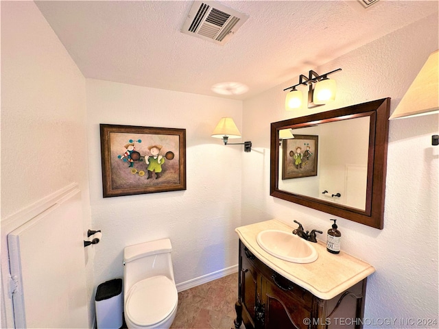 bathroom with toilet, a textured ceiling, and vanity