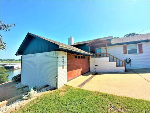 view of property exterior with a garage, a water view, and a lawn