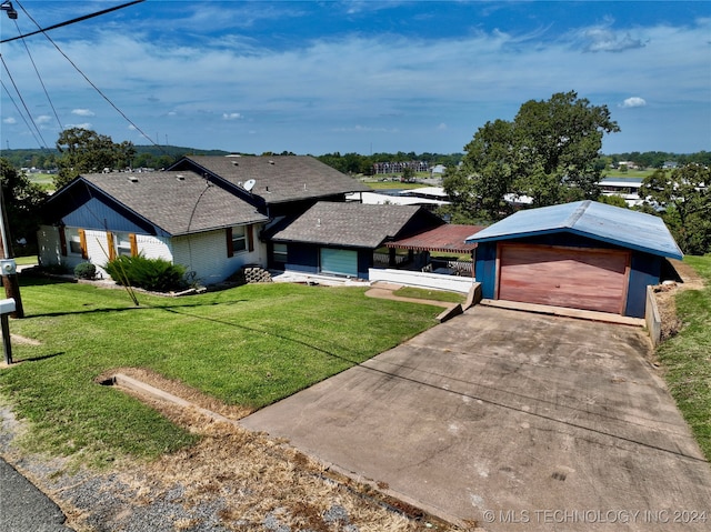 single story home featuring a front lawn, a garage, and an outbuilding