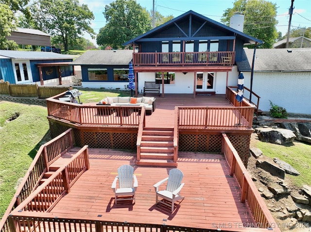 rear view of property with a wooden deck and a lawn