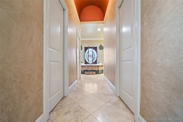 hall featuring light tile flooring and crown molding