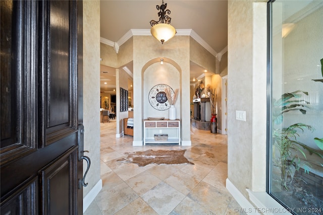 foyer with ornamental molding and light tile floors