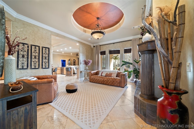 living room with crown molding, light tile floors, ceiling fan, decorative columns, and a raised ceiling