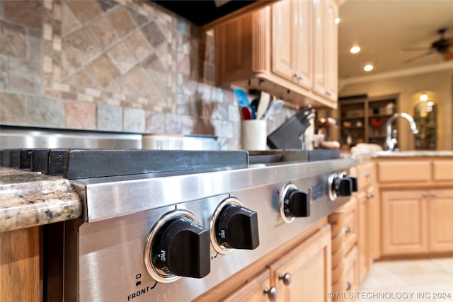 kitchen featuring backsplash, ornamental molding, ceiling fan, and sink