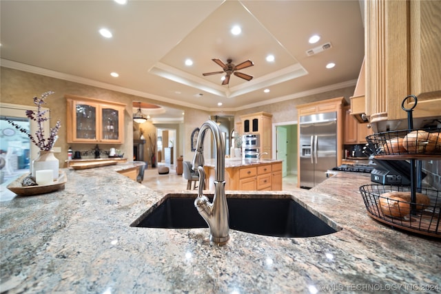 kitchen featuring light tile floors, light stone countertops, ceiling fan, built in fridge, and a tray ceiling