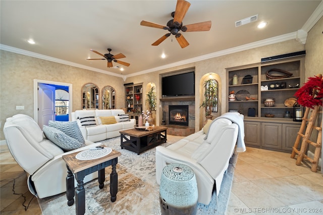 living room with ceiling fan, a tile fireplace, ornamental molding, and light tile floors