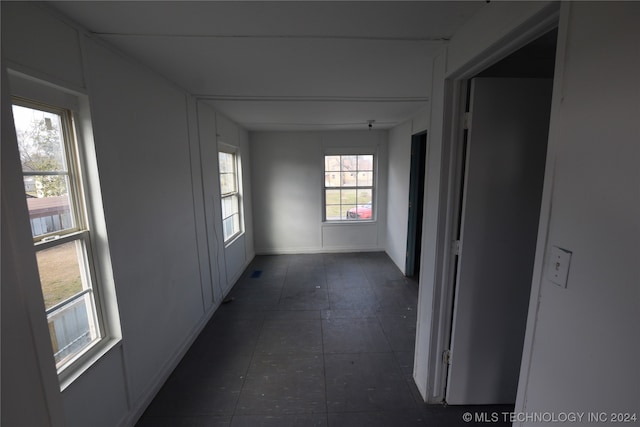 corridor featuring a healthy amount of sunlight and dark tile flooring