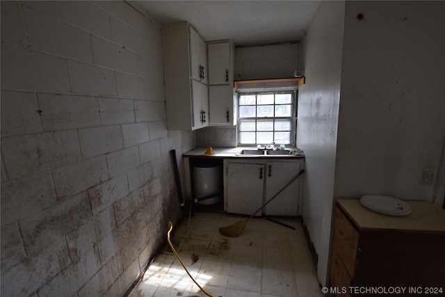 kitchen with white cabinetry, light tile floors, and sink