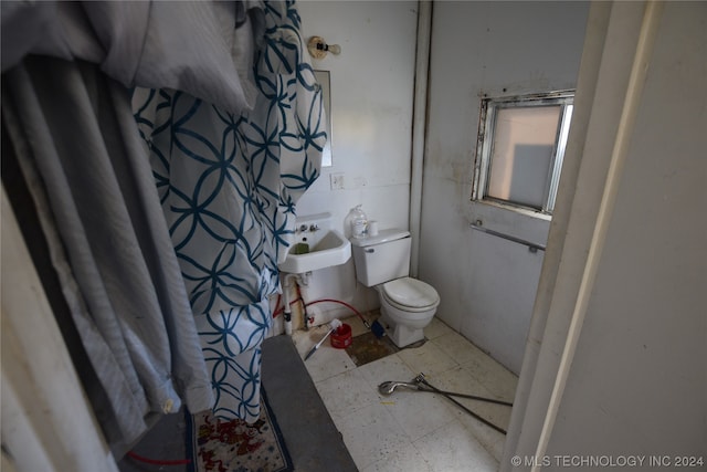 bathroom featuring toilet, sink, and tile flooring