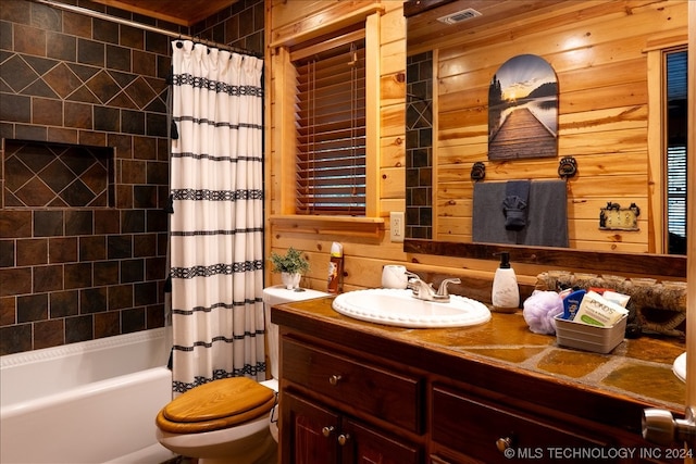 full bathroom with wood walls, toilet, shower / bath combo, and vanity with extensive cabinet space