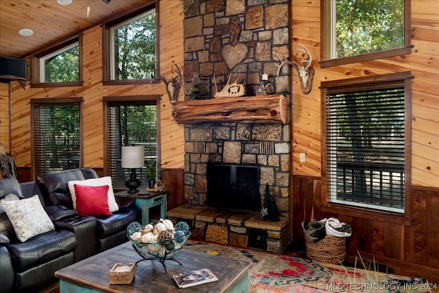 living room with lofted ceiling, wood ceiling, wooden walls, and a stone fireplace