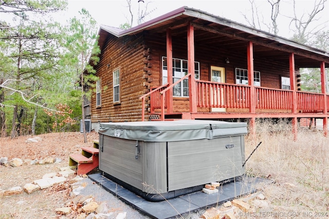 view of property exterior featuring a wooden deck and a hot tub