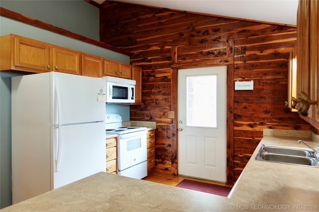 kitchen with white appliances, sink, light wood-type flooring, and wooden walls